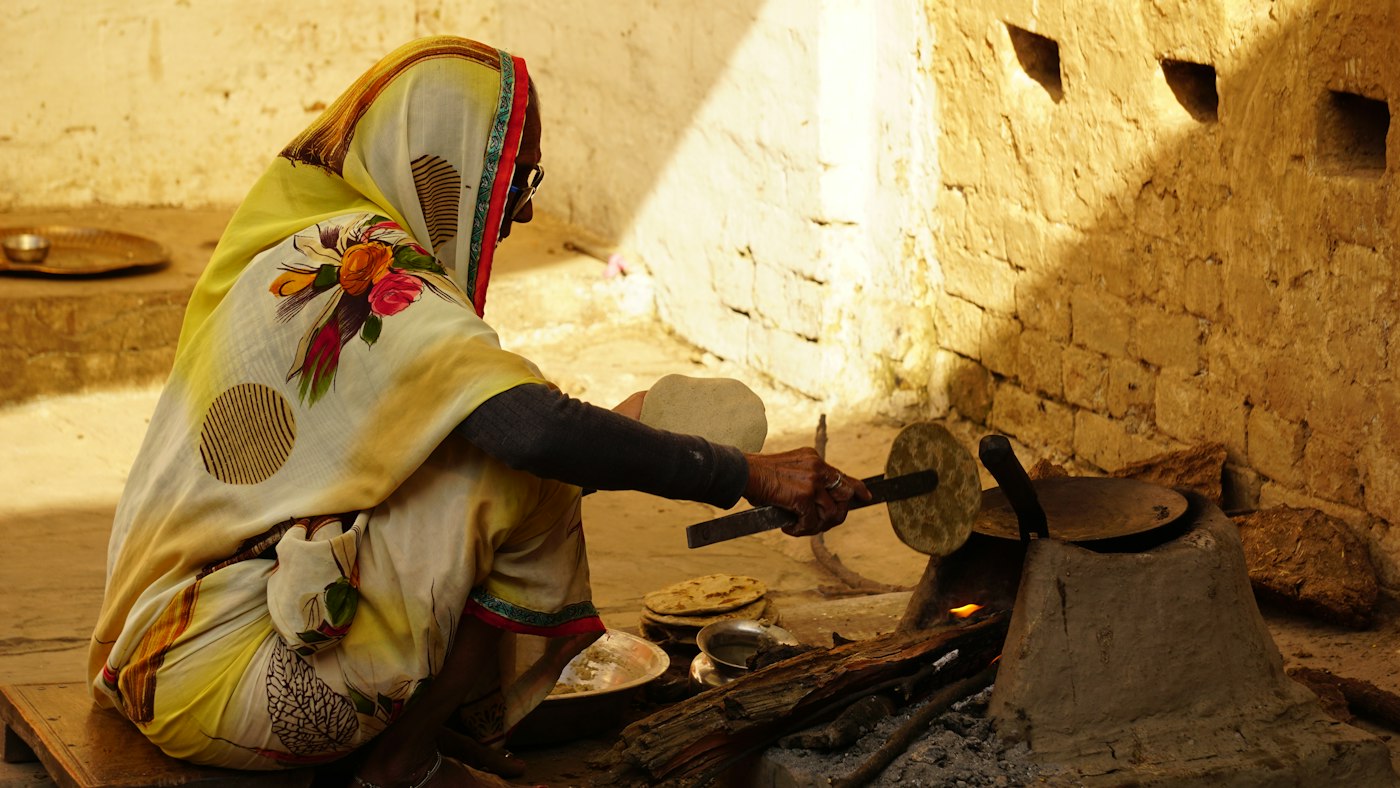 Woman making roti, Fatehpur, India A woman in a yellow and white sari making roti at home in a village in Fatehpur, India