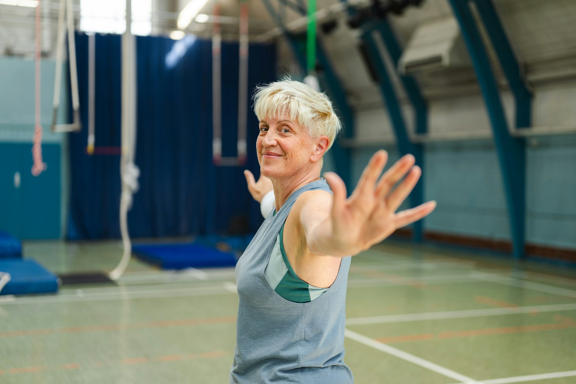 photo-1756314355668-7d3056db8600 An older woman with short blonde hair taking part in a at a gym.