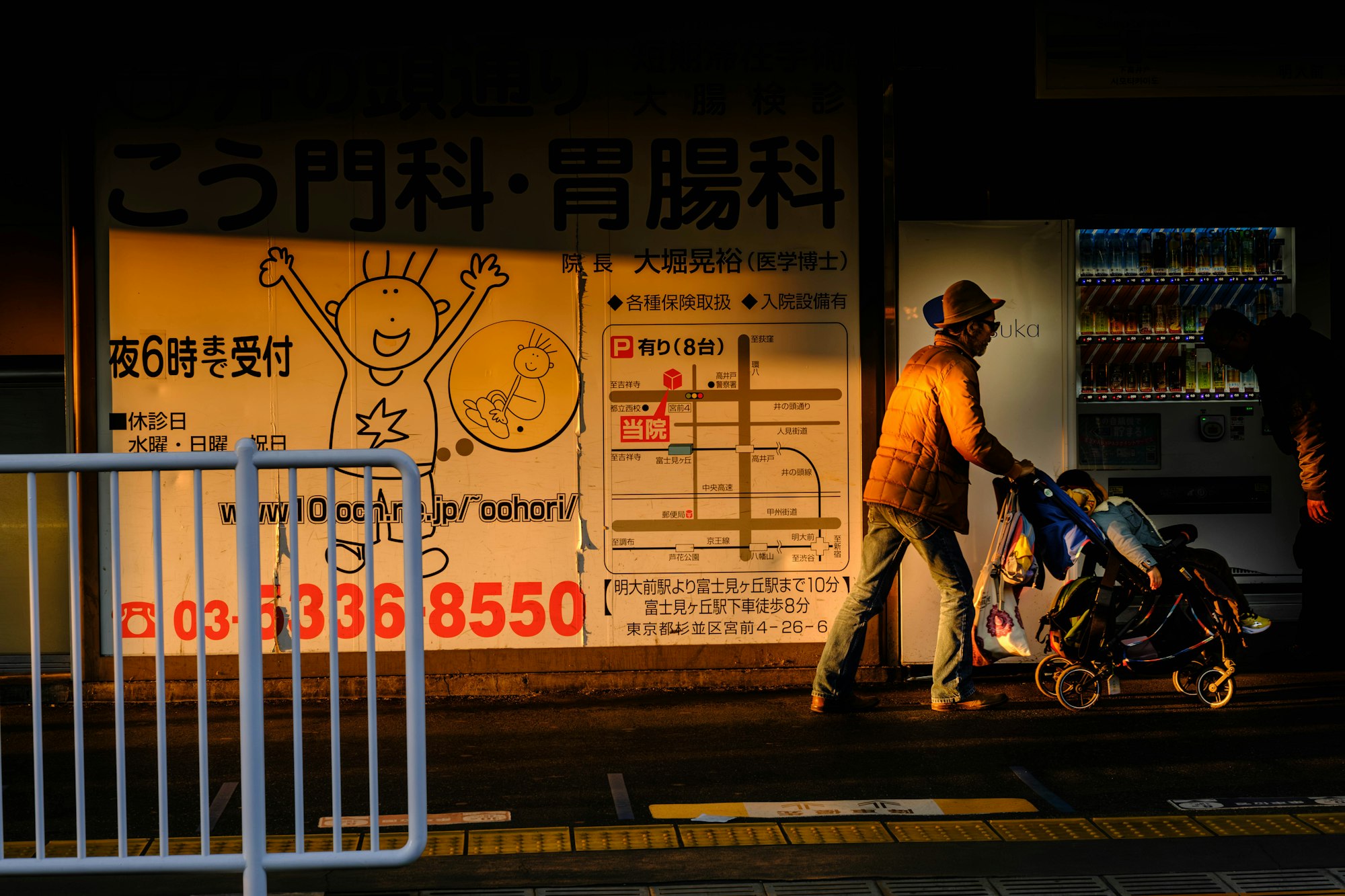 photo-1767613614537-5b26399eb7c4 A father pushes a baby in a stroller along a railway platform in Tokyo.